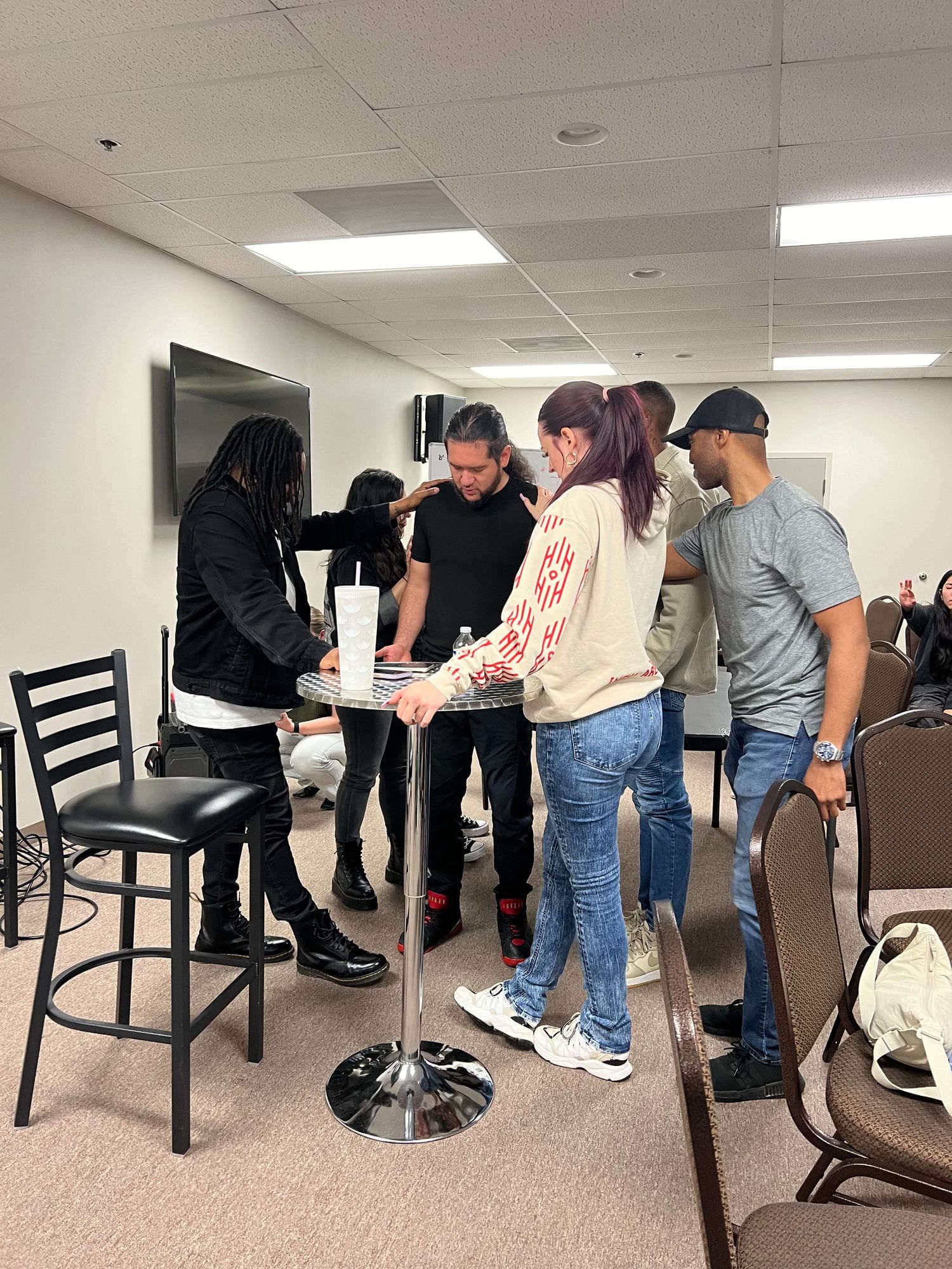 A small group praying together quietly, hands on each other's shoulders